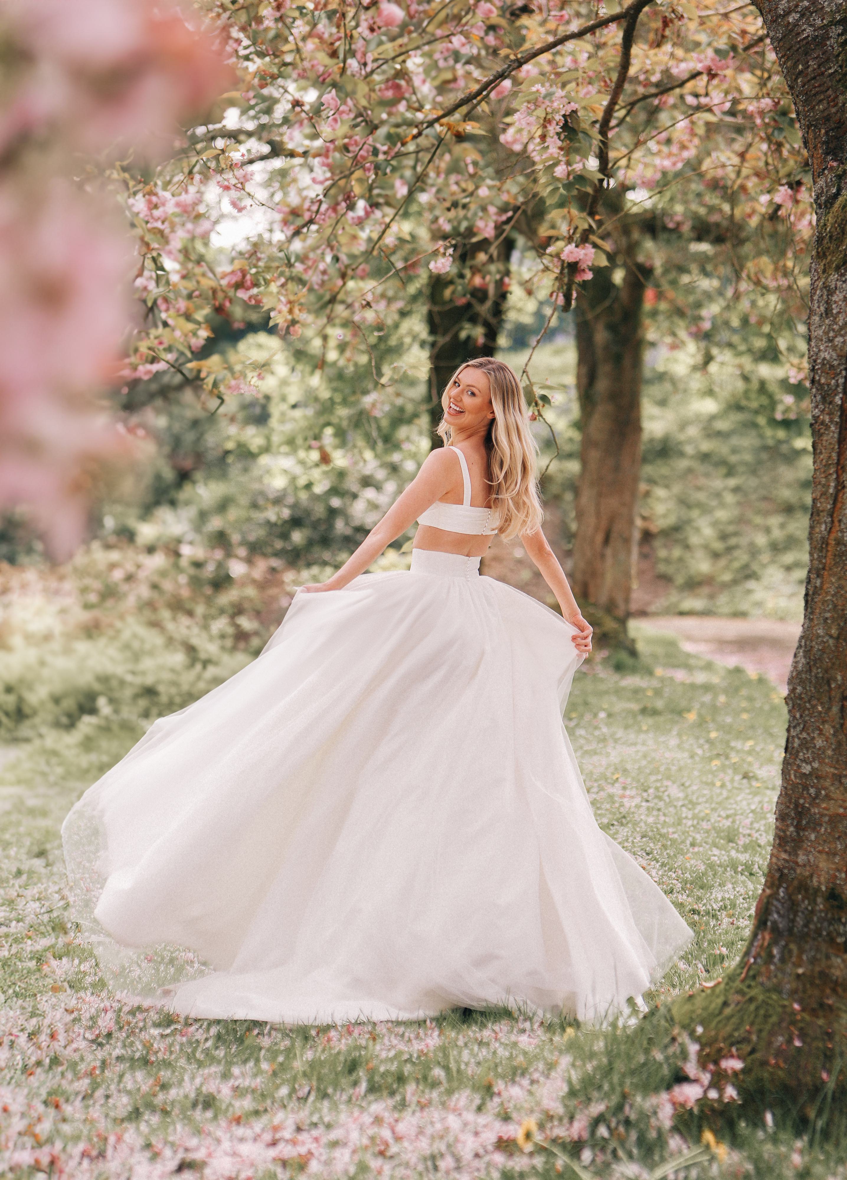 A charming two-piece wedding dress featuring a fitted crop top with wide straps and a high-waisted, full tulle skirt that flows beautifully, creating a romantic and airy silhouette.