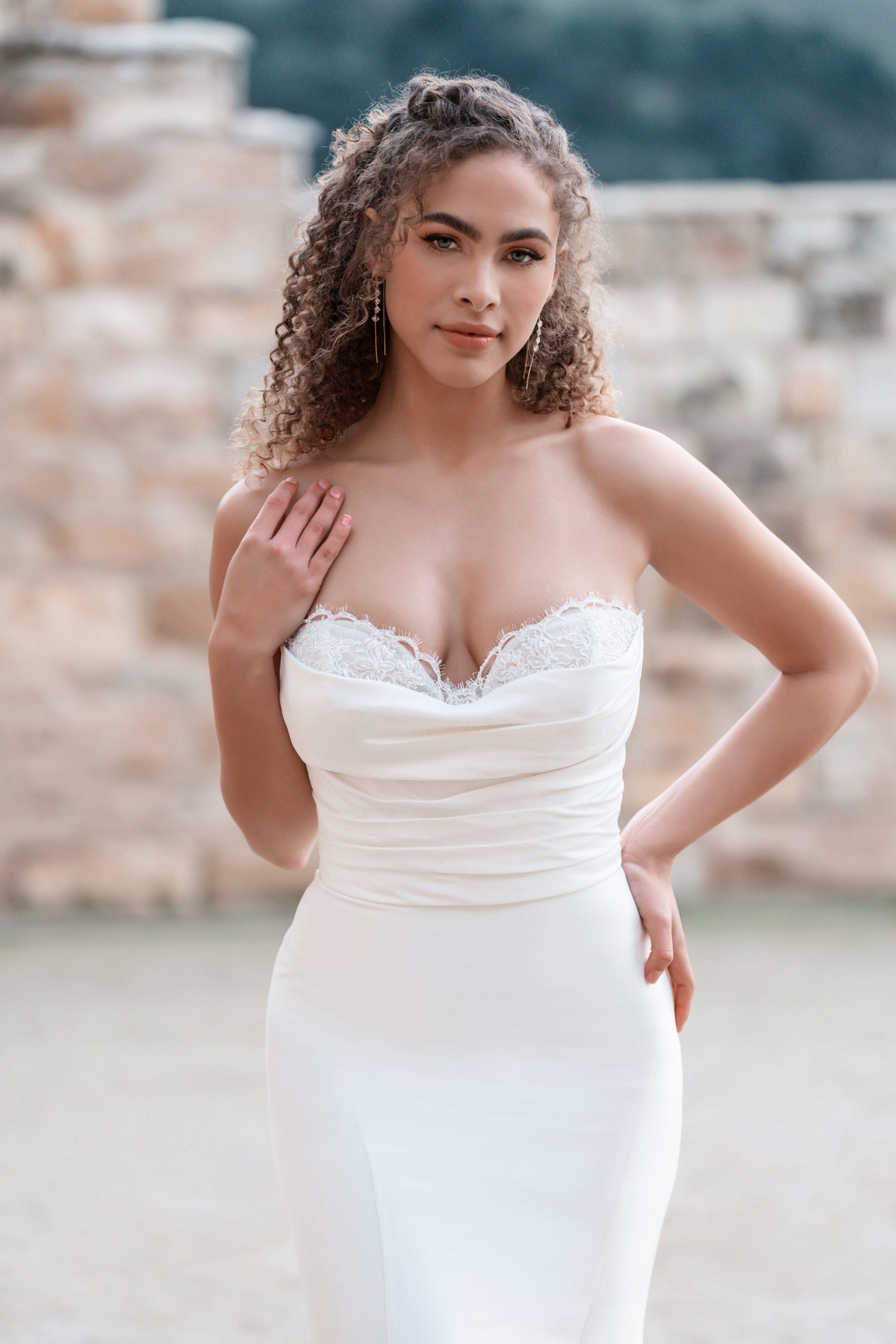 This Allure Bridals dress showcases a strapless design with a gently ruched bodice and a lace-trimmed sweetheart neckline. The bodice hugs the torso, highlighting a feminine silhouette, and the soft, intricate lace detailing adds a touch of romance and elegance. The fabric smoothly transitions into a fitted skirt, emphasizing a classic and sophisticated bridal look.