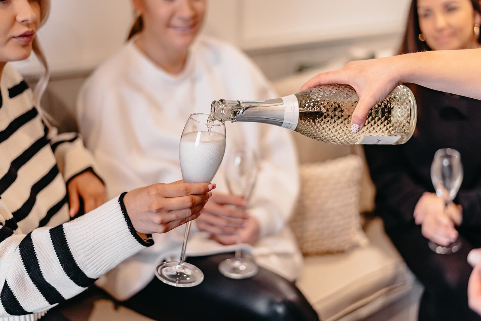 Pouring a bottle of fizz into flutes to celebrate the bride finding her dream wedding dress